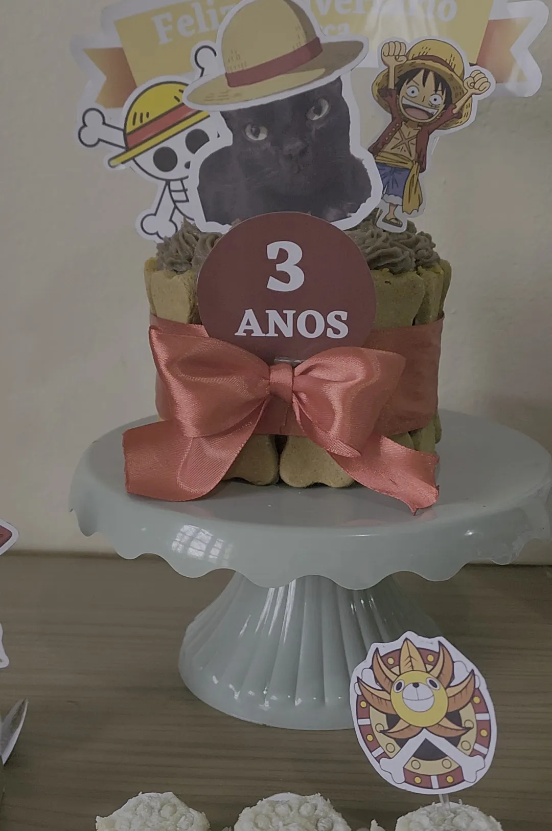 Docinhos com patinha em forminhas brancas, ao lado do bolo