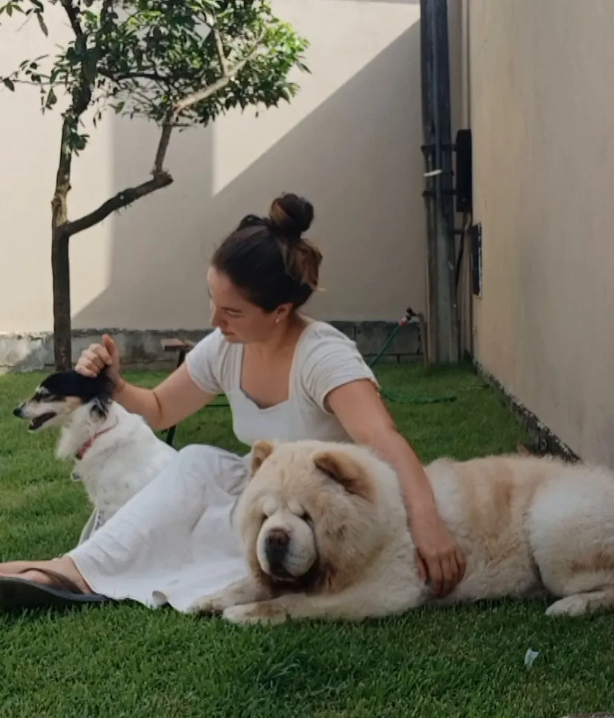Fernanda Ferrari sentada no gramado com dois cães hospedados